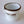 Load image into Gallery viewer, A three-quarter view of Fault Line's white enamel mug. The mug has a black lip. The front of the mug has a black Fault line logo on it.