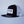 Load image into Gallery viewer, A three-quarter view of Fault Line's black & white snapback trucker cap. The front of the cap has an embroidered patch with the logo on it.