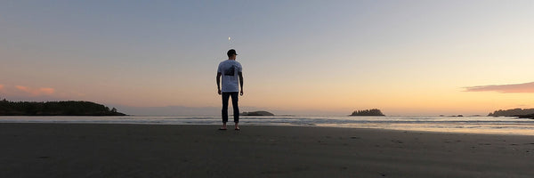 A solitary man stood on a beach at twilight