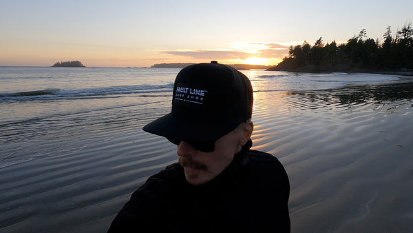 A close up of a man wearing a Fault Line trucker cap