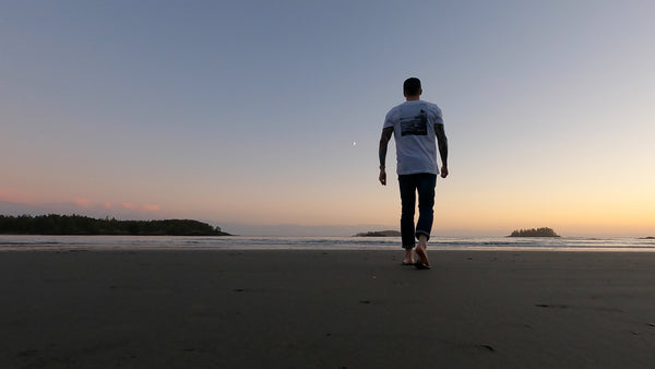 A solitary man walking on a beach at twilight