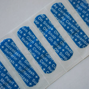 A close-up of six bandaids designed by Cut Again. Each bandaid has text printed multiple times on it. The text from bandaid one to six reads as follows - 1. son of a gun, 2. Ay caramba, 3. oh snap, 4. corn nuts, 5. sufferin succotash, 6. mother of pearl.