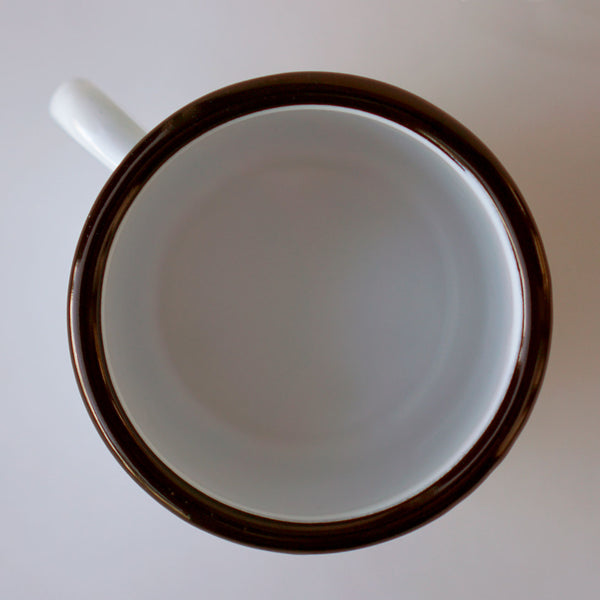 An overhead view of Fault Line's white enamel mug. The lip of the mug is black, the inside is white.