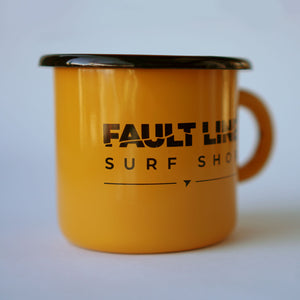 A side view of Fault Line's yellow enamel mug. The mug has a black lip. The front of the mug has a black Fault line logo on it.